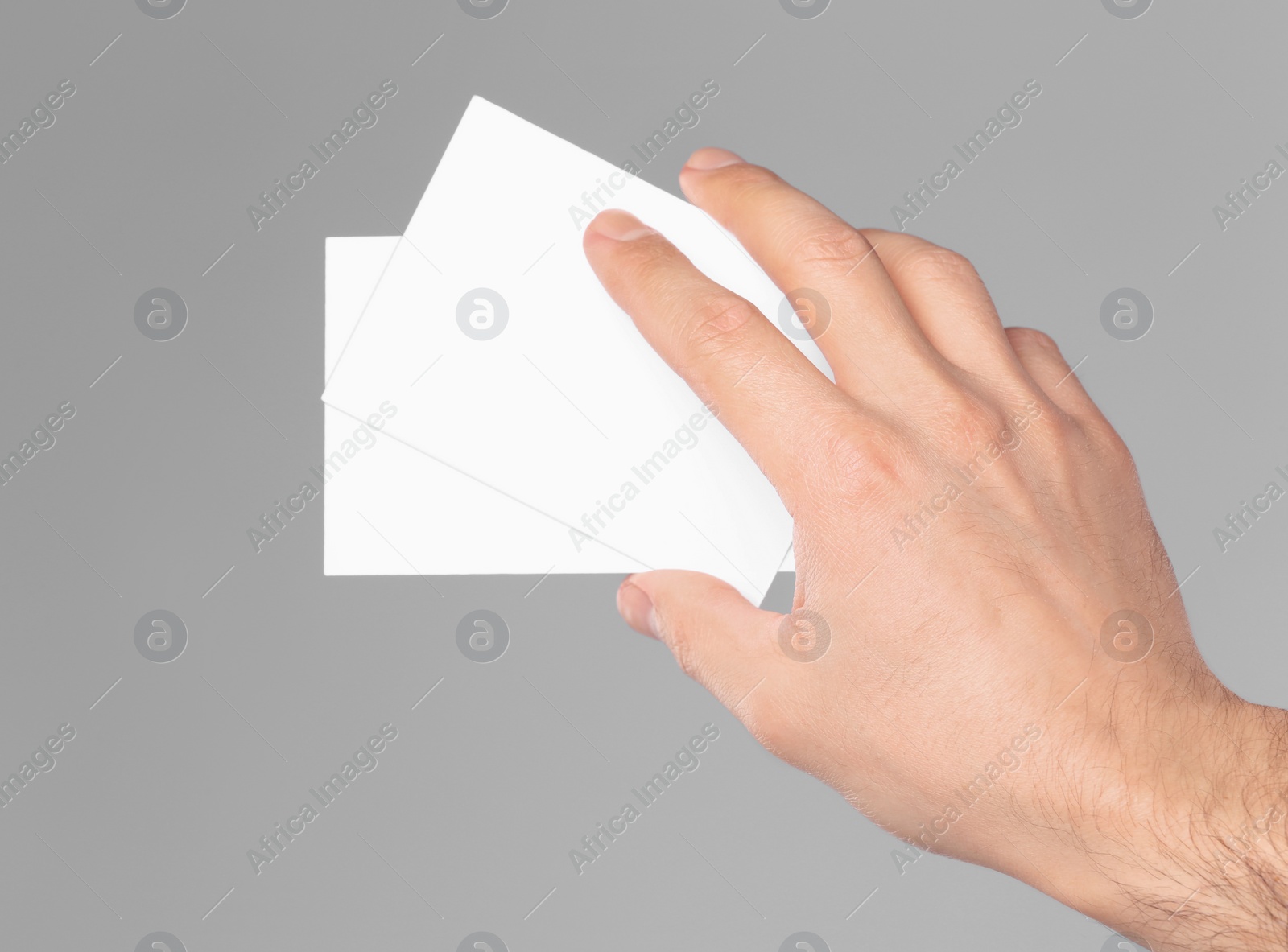 Photo of Man holding paper cards on grey background, closeup. Mockup for design