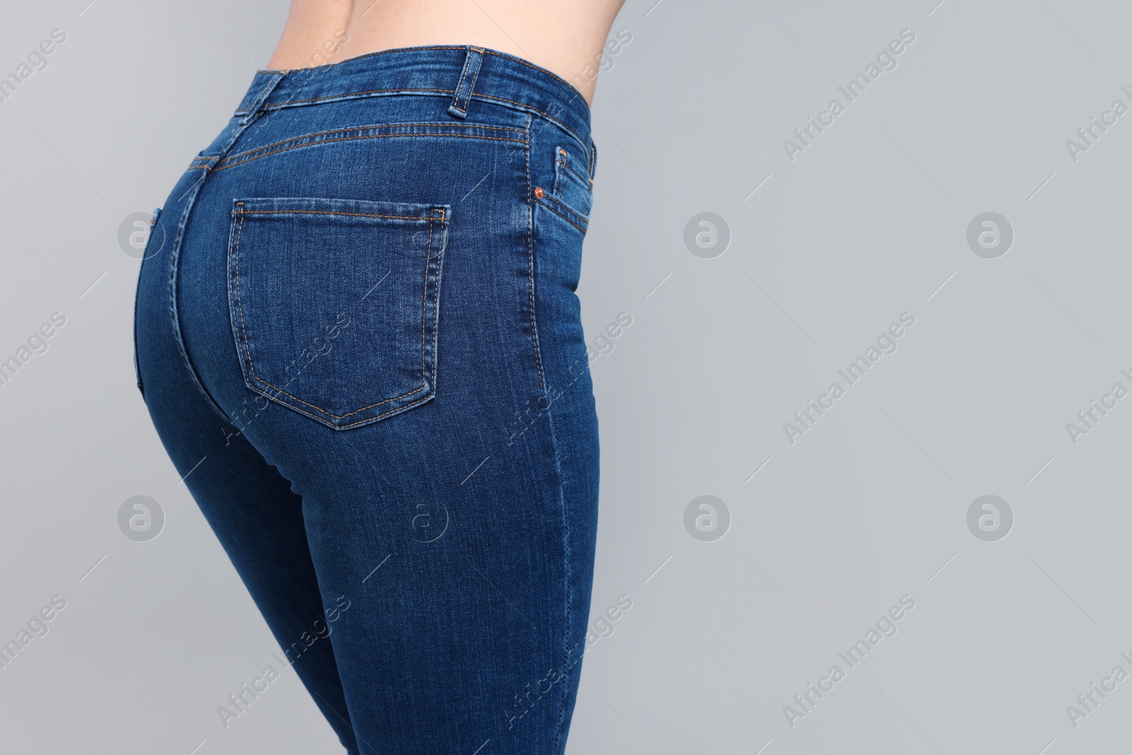 Photo of Woman in stylish jeans on grey background, closeup. Space for text