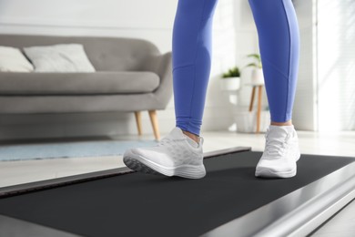 Photo of Sporty woman training on walking treadmill at home, closeup