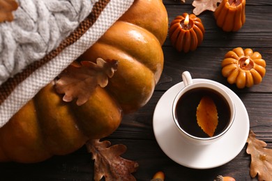 Cup of hot drink and pumpkin shaped candles on wooden table, above view. Cozy autumn atmosphere