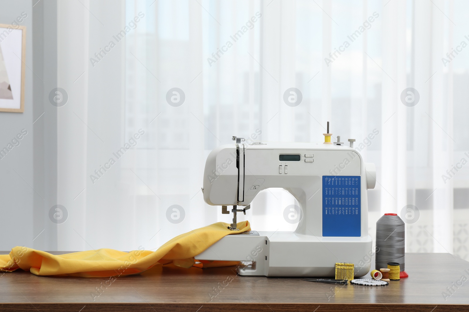 Photo of Sewing machine with fabric and craft accessories on wooden table indoors