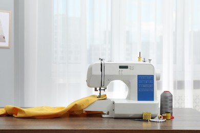 Sewing machine with fabric and craft accessories on wooden table indoors