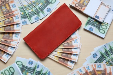Wallet and different Euro banknotes on wooden table, flat lay. Money exchange