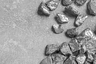 Photo of Pile of silver nuggets on light grey table, above view. Space for text