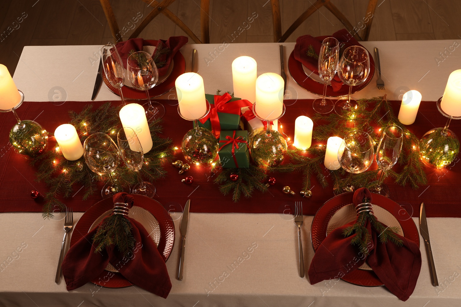 Photo of Christmas table setting with burning candles and festive decor, above view