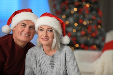 Photo of Happy mature couple in Santa hats at home. Christmas celebration