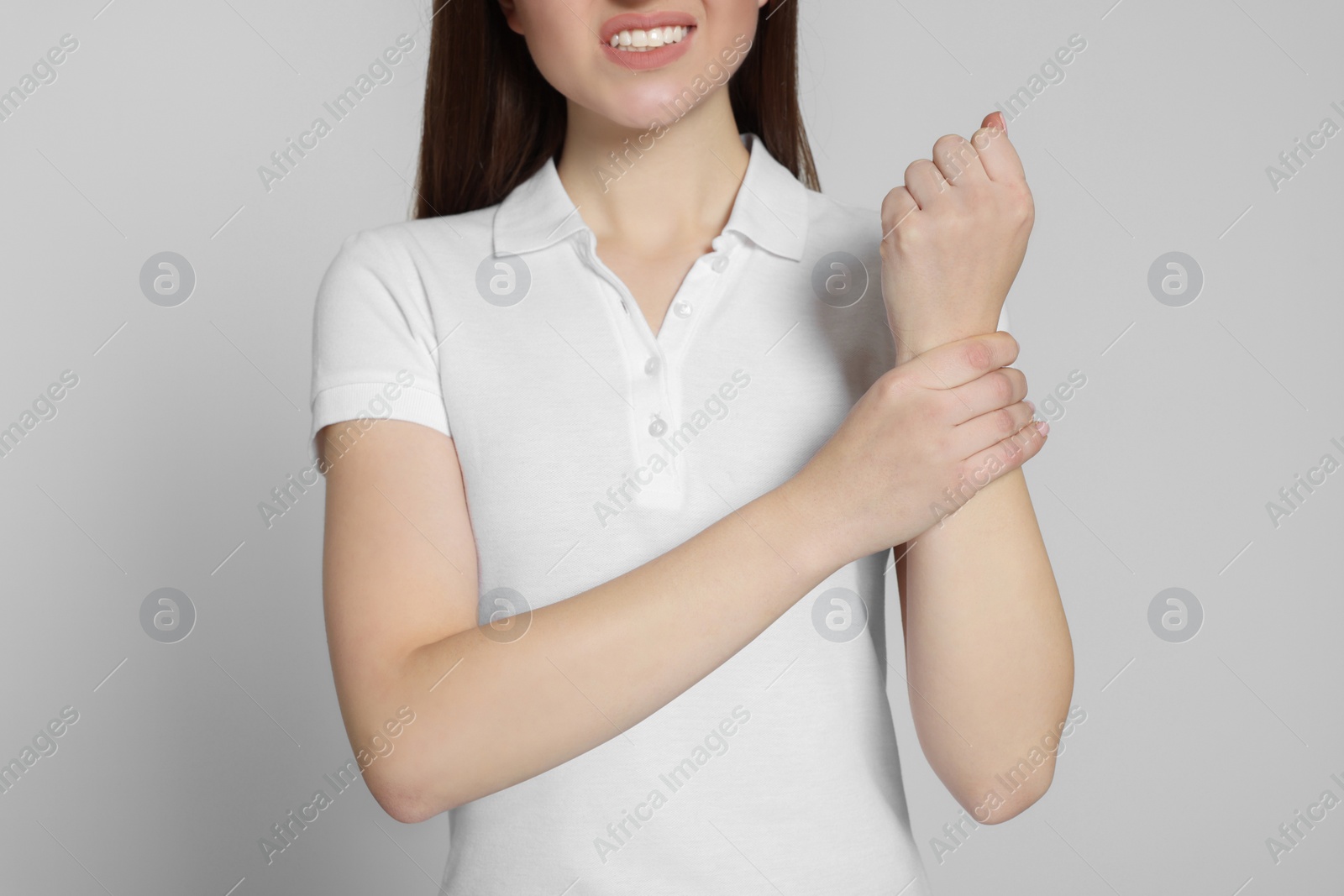 Photo of Woman suffering from pain in her hand on light grey background, closeup. Arthritis symptoms