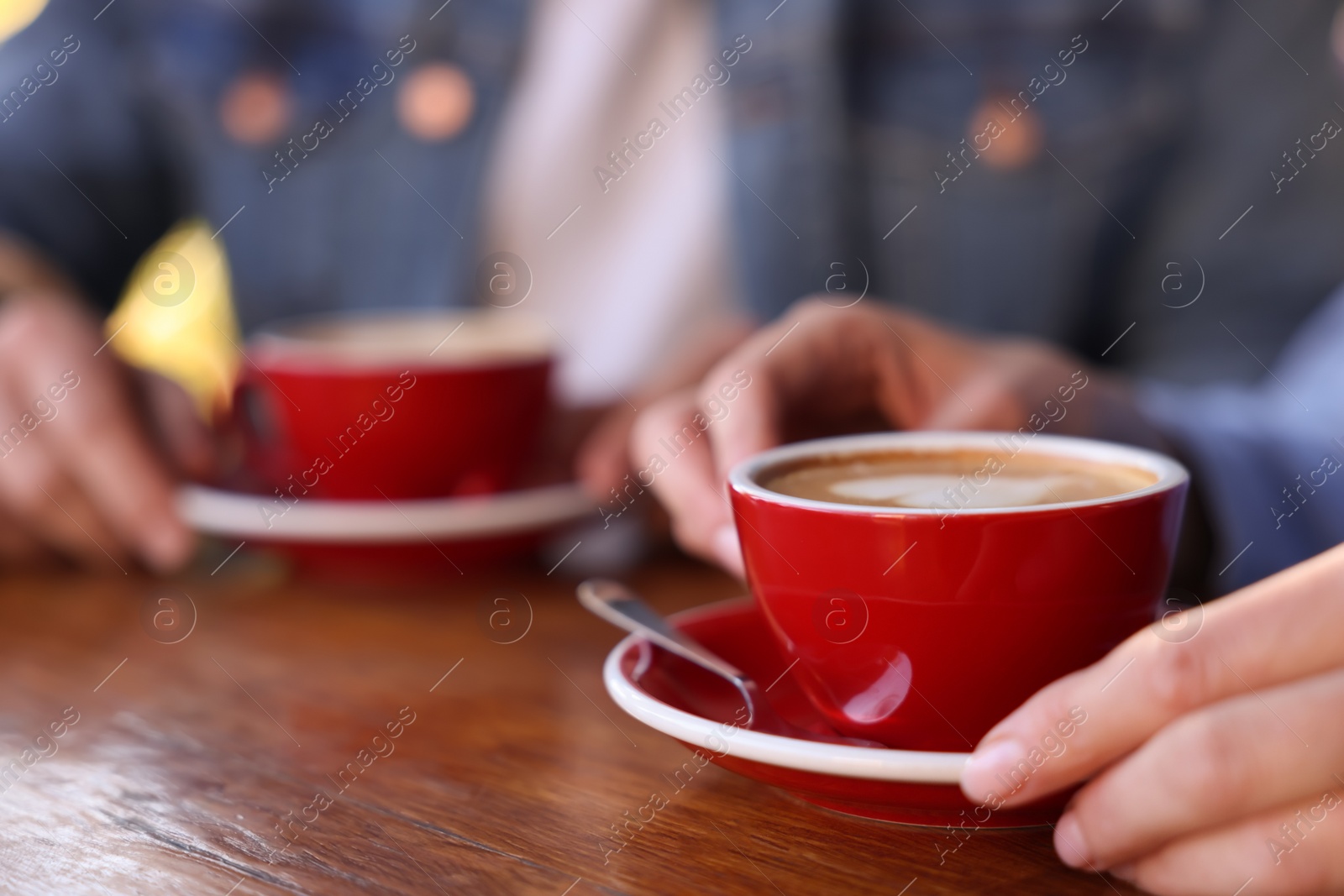 Photo of Couple with cups of aromatic coffee at wooden table, closeup