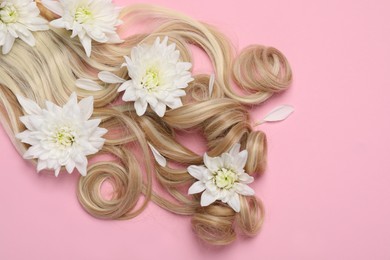 Photo of Lock of healthy blond hair with flowers on pink background, flat lay. Space for text