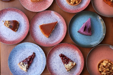 Photo of Plates with different cakes on wooden table, top view