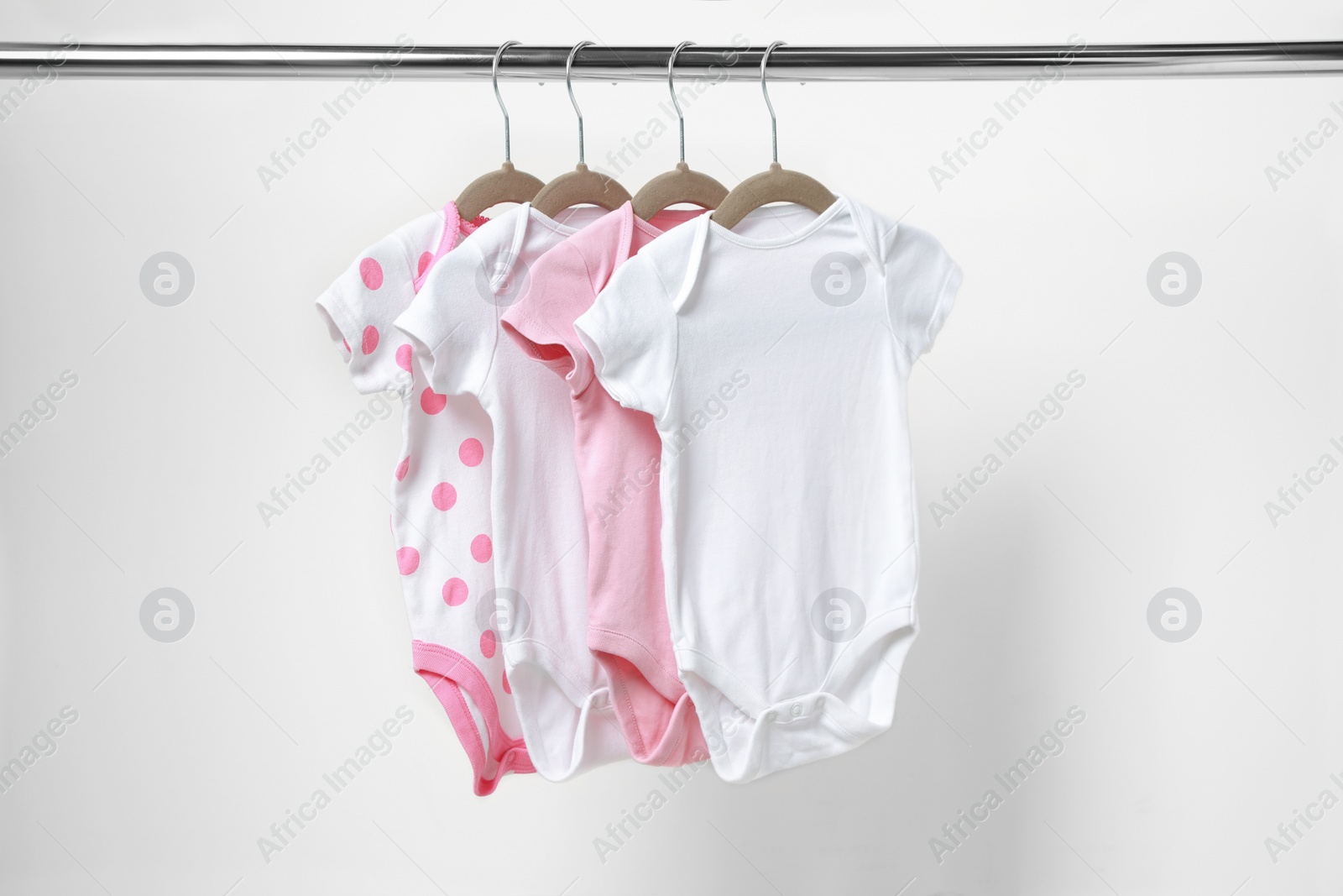 Photo of Baby bodysuits hanging on rack near white wall