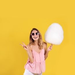 Photo of Happy young woman with cotton candy on yellow background