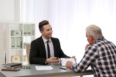 Photo of Young lawyer having meeting with senior client in office