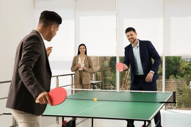 Photo of Business people playing ping pong in office