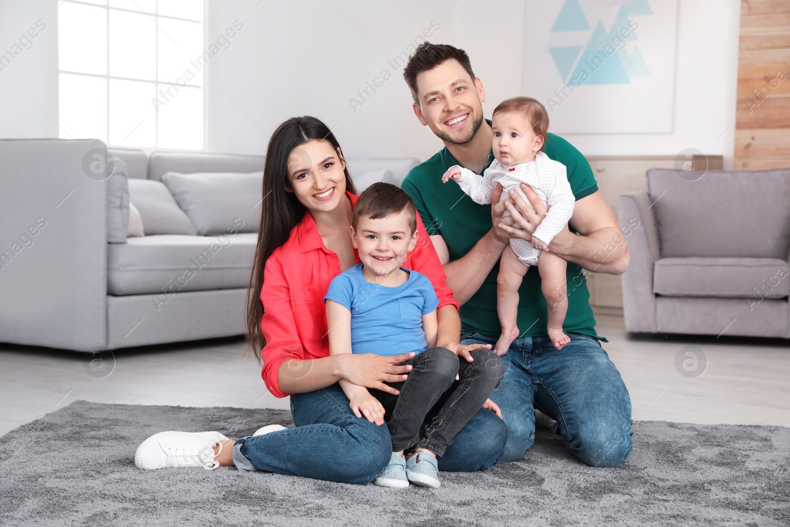 Photo of Happy parents and their cute children sitting on floor at home. Family time