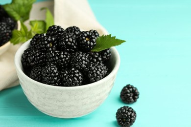 Bowl of fresh ripe blackberries on turquoise wooden table, closeup. Space for text