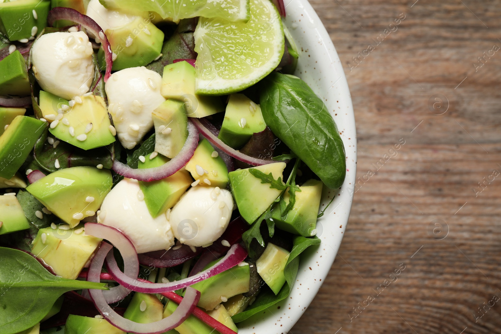 Photo of Delicious avocado salad with mozzarella on wooden table, top view