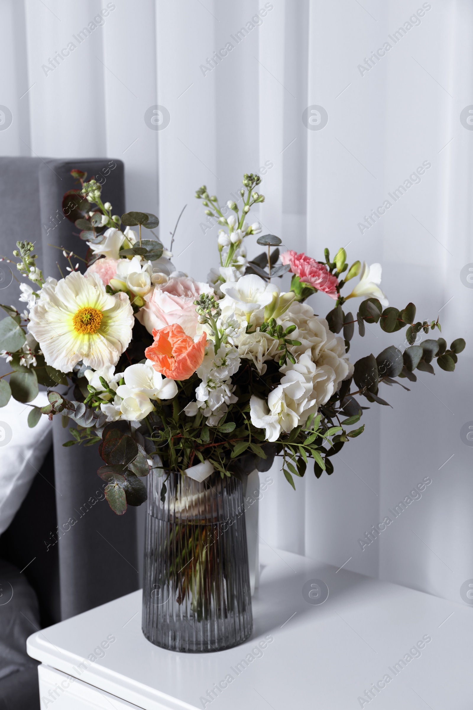 Photo of Bouquet of beautiful flowers on nightstand indoors