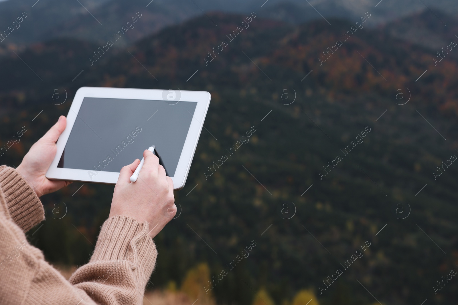 Photo of Young woman drawing on tablet in mountains, closeup. Space for text