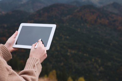 Young woman drawing on tablet in mountains, closeup. Space for text