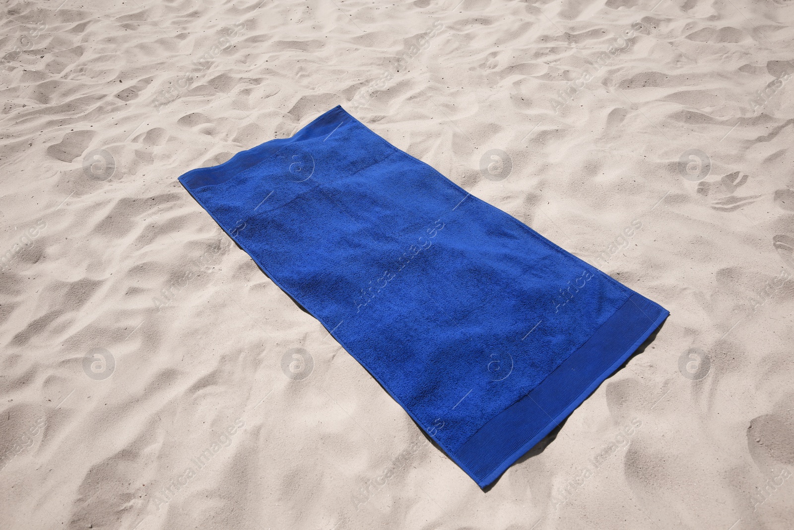 Photo of Beautiful soft blue beach towel on sand