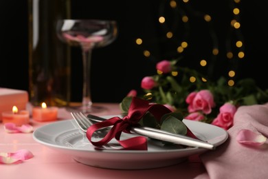 Photo of Place setting with roses and candles on pink wooden table, closeup. Romantic dinner