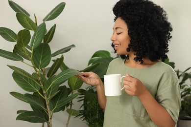 Photo of Relaxing atmosphere. Happy woman with cup of hot drink near beautiful houseplants