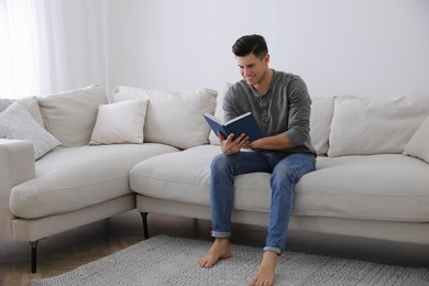 Photo of Man with book sitting on comfortable sofa in living room