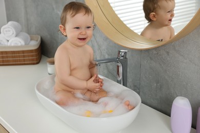 Photo of Cute little baby bathing in sink at home