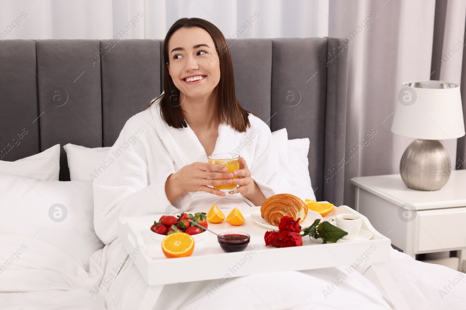 Photo of Smiling woman having breakfast in bed at home