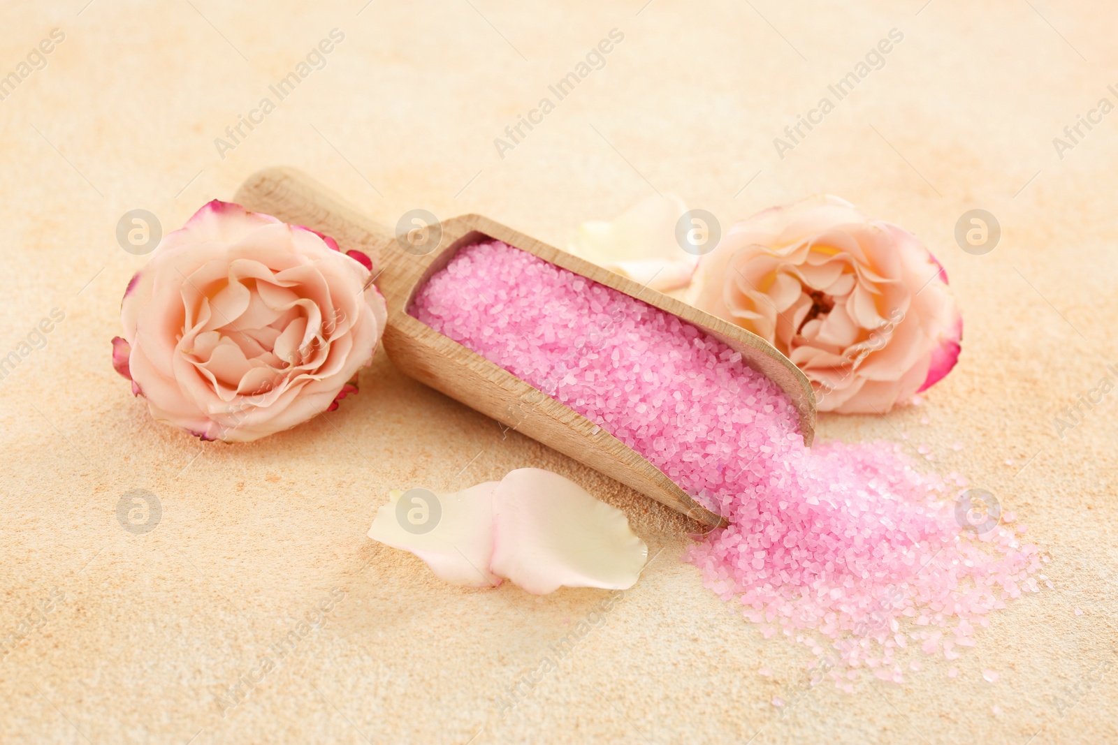 Photo of Pink sea salt and beautiful flowers on color textured table
