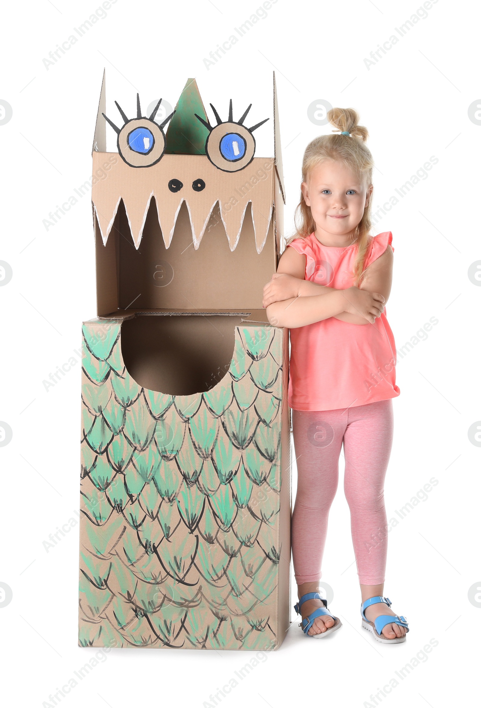 Photo of Cute little girl playing with cardboard dragon on white background