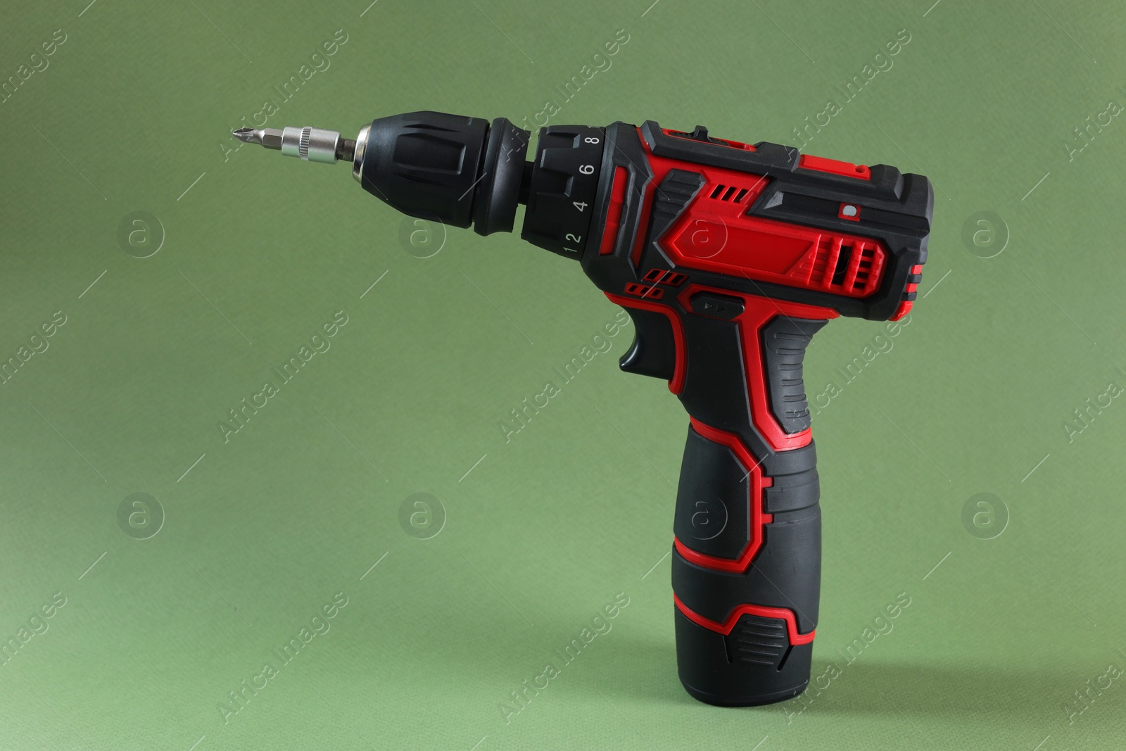 Photo of Modern electric screwdriver on pale green background