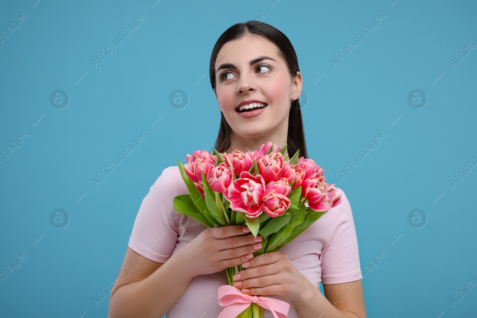 Photo of Happy young woman with beautiful bouquet on light blue background