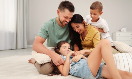 Image of Happy family with children having fun on floor in bedroom
