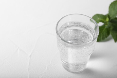 Photo of Glass of soda water on white table, closeup. Space for text
