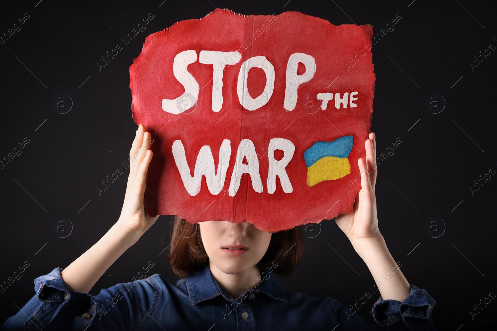 Photo of Sad woman holding poster with words Stop the War on black background