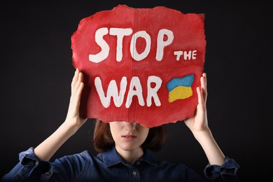 Photo of Sad woman holding poster with words Stop the War on black background