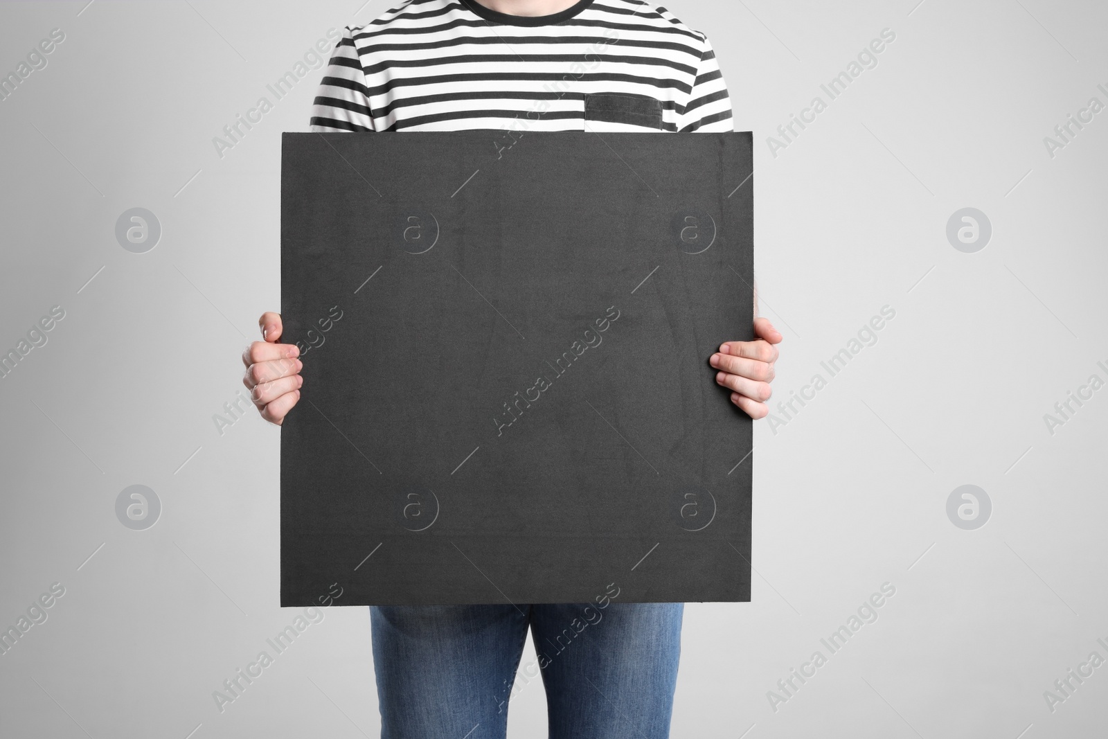 Photo of Man holding blank poster on light grey background, closeup