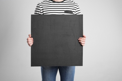 Photo of Man holding blank poster on light grey background, closeup