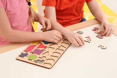 Children playing with math game kit at desk indoors, closeup. Learning mathematics with fun