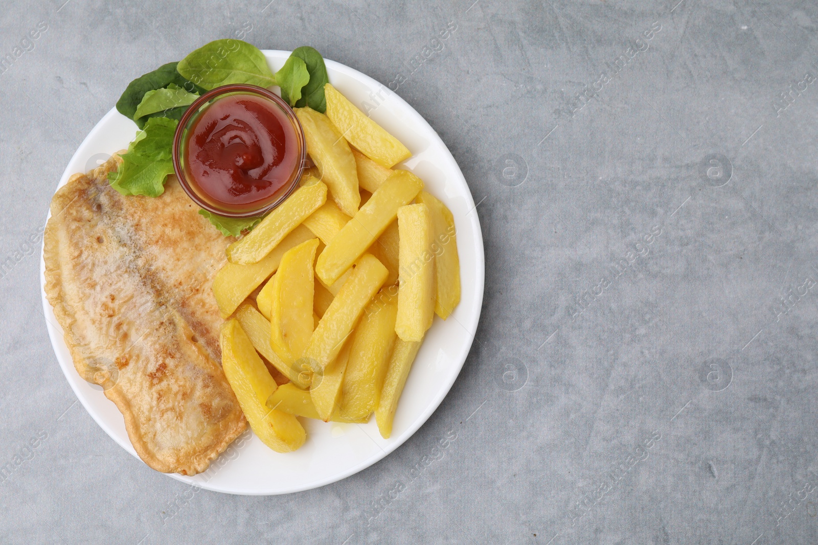 Photo of Delicious fish and chips with ketchup, spinach and lettuce on gray table, top view. Space for text