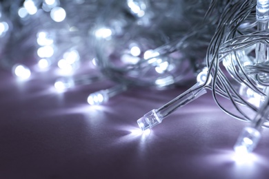 Glowing Christmas lights on violet background, closeup