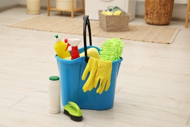 Different cleaning products and bucket on floor indoors