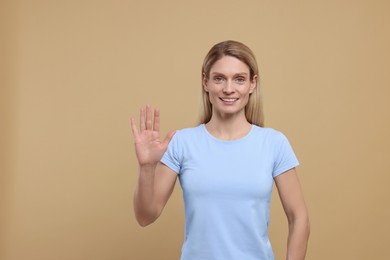 Photo of Woman giving high five on light brown background