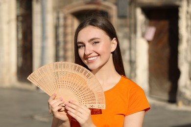Photo of Happy woman holding hand fan on city street