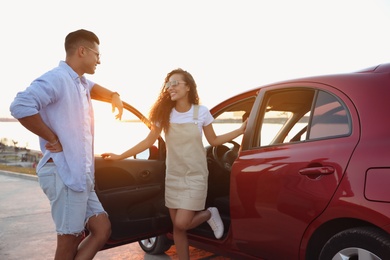 Photo of Happy couple near car outdoors at sunset. Summer trip