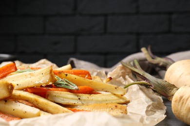 Photo of Tasty baked parsnip and bell pepper on parchment, closeup. Space for text