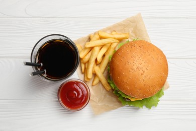 French fries, tasty burger, sauce and drink on white wooden table, flat lay
