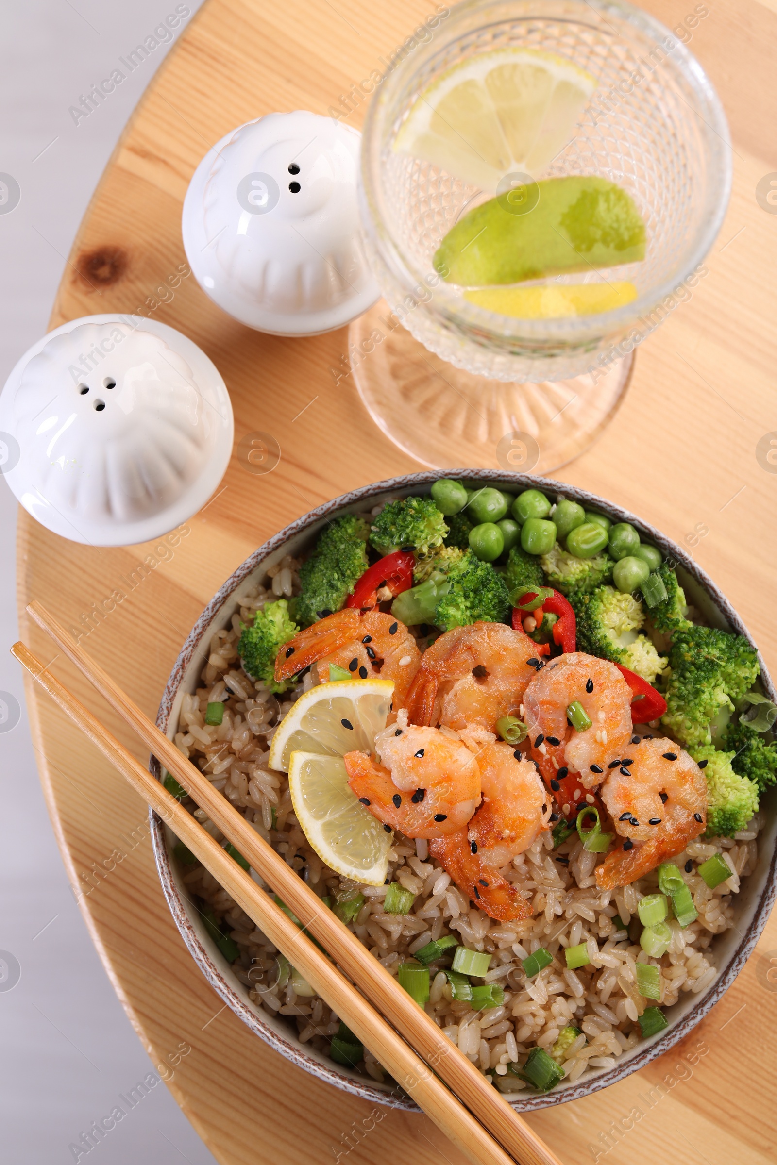 Photo of Tasty rice with shrimps and vegetables served on wooden table, flat lay